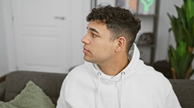 Modern bir apartman dairesinde kapüşonlu giyen kıvırcık saçlı yakışıklı bir genç..