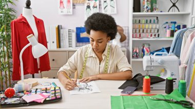 Afrikalı Amerikalı kadın terzi iyi donanımlı bir atölyede moda tasarlıyor.
