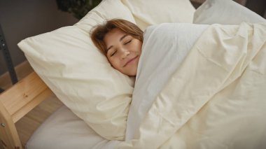 Huzurlu genç bir kadın, yatak odası ortamında rahatça dinlenirken, rahatlık ve sükunetin bir örneğini verir..