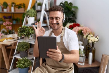 Çiçekçide çalışan İspanyol sakallı bir adam. Video çekiyor. Parmaklarıyla imza atıyor. 