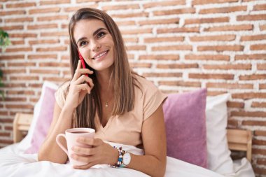 Genç, güzel, İspanyol bir kadın. Akıllı telefondan konuşuyor. Yatak odasında kahve içiyor.