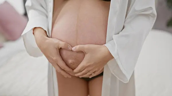 Mladá Hispánka Objímající Své Těhotné Břicho Když Sedí Posteli Ukazuje — Stock fotografie