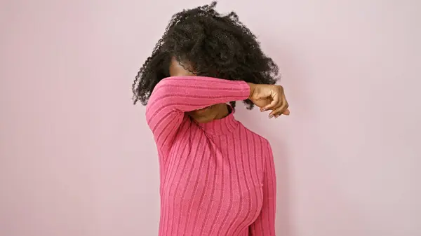 stock image Black woman covering eyes with arm against pink background, depicting emotion or headache