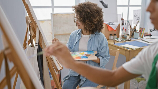 At the heart of creativity, man and woman artists, drawing together at an art studio, immersed in a world of paint, canvas, and relaxed concentration.