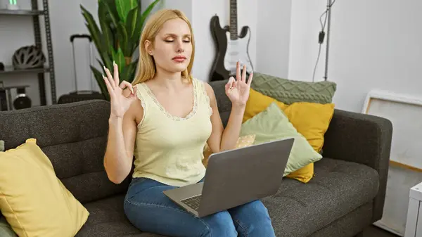 Rolig Blond Kvinne Praktiserer Meditasjon Sofa Med Bærbar Moderne Stue – stockfoto