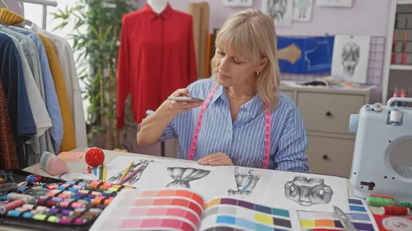 stock image A focused caucasian woman reviews fashion designs in a well-equipped tailor shop with colorful fabric swatches