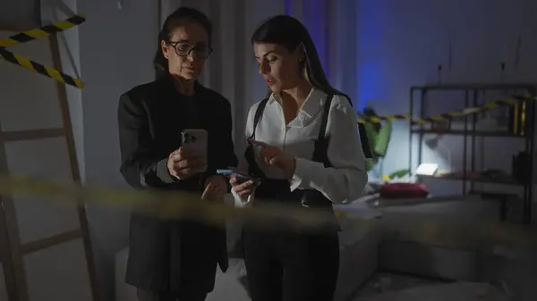 Two Women Investigators Examine Evidence Using Smartphones Dimly Lit Room — Stock Photo, Image