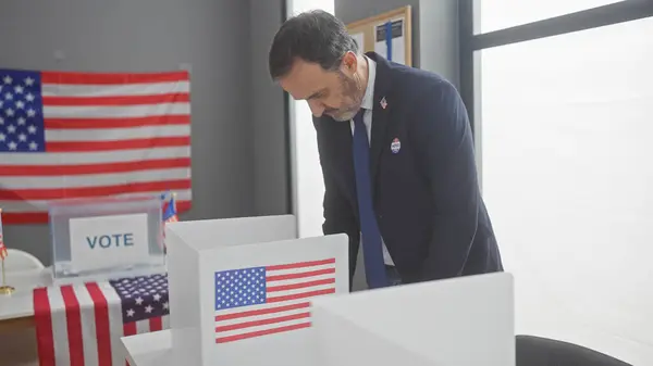 stock image Mature bearded man voting in american electoral room with flags