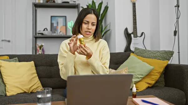 히스패닉 여성은 배경에 노트북과 기타와 아늑한 거실에 앉아있는 스톡 사진