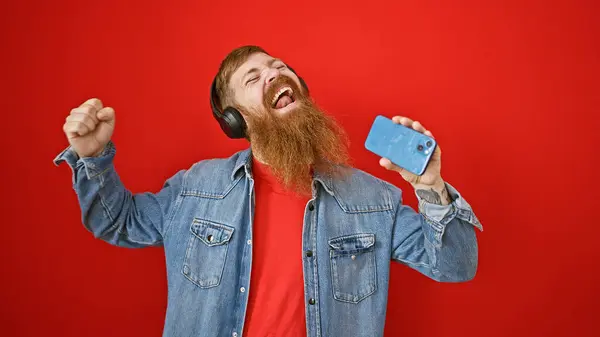 Pemuda Berambut Merah Yang Percaya Diri Tersenyum Dengan Earphone Menyanyikan Stok Foto