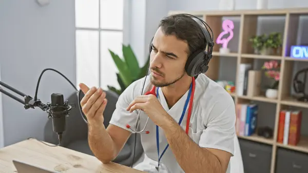 現代の屋内スタジオの設定でマイクに話すヘッドフォンを身に着けているハンサムなヒスパニック男性 ストック写真