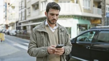 Meşgul şehir caddesinde akıllı telefon kullanan yakışıklı İspanyol.