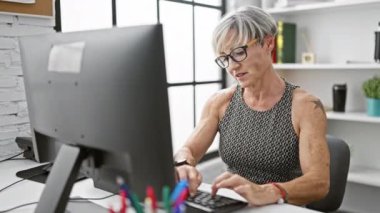 Olgun kadın, ofis içinde heyecanlı bir ifadeyle işteki başarısını kutluyor..