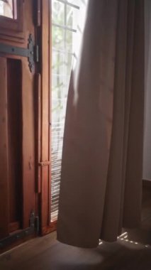 Güneş ışığı ahşap bir pencereden süzülür ve panjurlar, bir perdeye gölgeler ve rahat, sakin bir odada ahşap zemin..