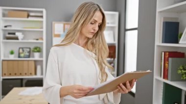 Profesyonel genç bir kadın modern ofis ortamında belgeleri inceliyor. İş, planlama ve organizasyon öneriyor..