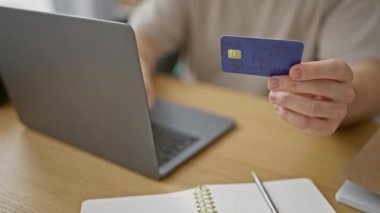 Ofiste kredi kartı tutan beyaz adam online ödeme konseptini sergiliyor..