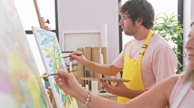 İki kendine güvenen sanatçı, erkek ve kadın, sanat stüdyosunda neşeyle çizim yapıyorlar.