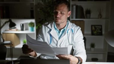 Odaklanmış bir İspanyol doktor gece geç saatlerde klinikte evrak işlerini analiz eder. Sağlık hizmetleri ve adanmışlığı gösterir..