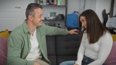 Gülümseyen adam ve kadın neşeli bir anın tadını çıkarıyorlar. Sıcak bir oturma odasında sarılıp gülüyorlar..