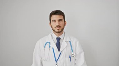 Neşeli genç İspanyol bir adam, steteskop takan gülümseyen bir doktor, şaşırtıcı bir şekilde izole edilmiş beyaz arka planı işaret ediyor. Olumlu bir sürpriz jest.!