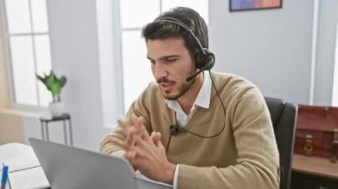 Modern bir ofiste video görüşmesinde kulaklık takan yakışıklı İspanyol bir adam..