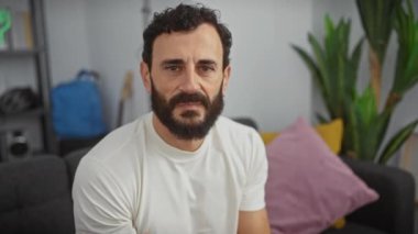 Orta yaşlı, sakallı yakışıklı, beyaz tişört giyen, sinsi bir sırrı fısıldayan, elleri kapalı bir yerde gevezelik eden bir adam. Evde baharatlı oturma odası sohbeti.!