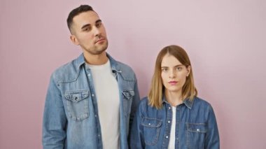 Kot gömlekli güzel bir çift pembe arka plandaki bir reklamı işaret ediyor. Sakin, sevgi dolu, izole bir duruşa güveniyorlar.