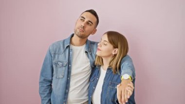 Acele et, saat son gün! Kot gömlekli güzel bir çift pembe izole edilmiş arka planda duruyorlar, işe geç kalıyorlar, kol saatini ciddi bir dakiklikle kontrol ediyorlar..