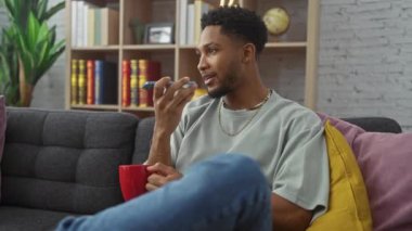 Afro-Amerikalı adam evde akıllı telefon kullanıyor, gündelik, modern, teknoloji, konforlu, sesli mesaj, iç mekan, yaşam tarzı, rahatlama, iletişim