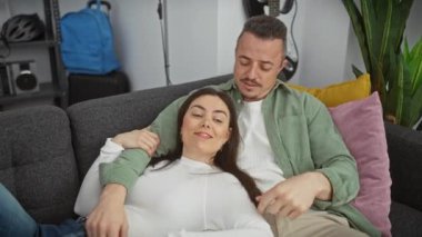 Sevgi dolu bir çift, rahat bir oturma odasında, gri bir kanepede rahatlar, rahatlık ve yakınlık hissi yaratır..