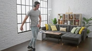 Genç İspanyol bir adam modern stil bir salonda tek başına dans etmekten zevk alıyor. Mutluluk ve rahatlık saçıyor..