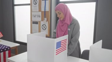 Kendine güvenen, tesettürlü bir İspanyol kadın oy kabininde Amerikan bayrağı ve 