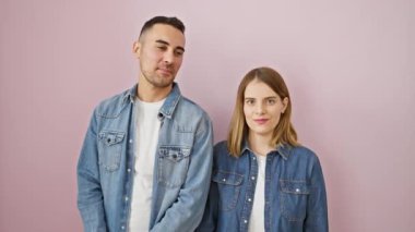 Kot gömlekli güzel bir çift, çılgın, eğlenceli bir mutluluk ifadesi için dil çıkarıyorlar! Pembe izole bir arka planda mutlu bir şekilde duruyoruz..