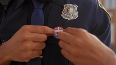 Afrika kökenli Amerikalı erkek polis memuru. Kapalı alanda üniformaya etiket yapıştırdım.