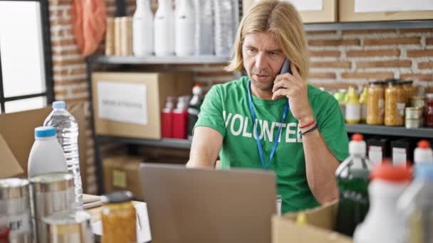 Volunteer Man Long Blond Hair Talks Phone While Working Laptop — Stock Video