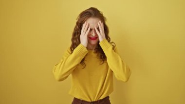 Ayakta duran güzel genç bir kadın, el üstünde, migren ağrısı çekiyor, sarı izole arka planda strese yol açan baş ağrısı.