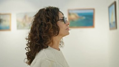 Olgun İspanyol kadın bir sanat galerisinde resim yapmayı düşünüyor. Kültür ve takdir duygusunu çağrıştırıyor..