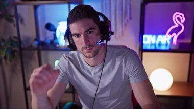 Geceleri renkli bir oyun odasında kulaklıklı, odaklanmış İspanyol bir adam..