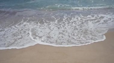 Köpüklü deniz suyu sakin bir sahilde el değmemiş kumların üzerinde yavaşça süzülür..