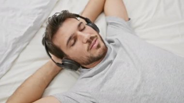 Rahat, genç bir İspanyol, rahat bir yatak odasında yatarken kulaklıkla müzik dinlemekten hoşlanır..