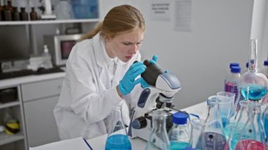 Laboratuvarda mikroskop kullanan beyaz kadın bilim adamı.