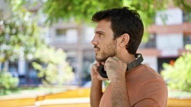 Kulaklık takan yakışıklı bir İspanyol, şehir parkında müzik dinlemekten hoşlanıyor..