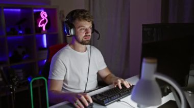 Gece vakti, parlak neon ışıkları olan karanlık bir odada sakallı yakışıklı bir genç.