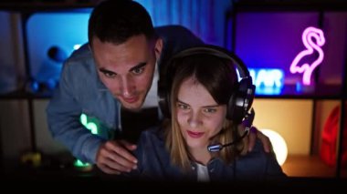 Bir erkek ve bir kadın, aydınlık bilgisayar ekranlarıyla geceleri evlerinde oyun oynamaktan zevk alırlar..