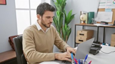Modern ofis ortamında dizüstü bilgisayarla çalışan sakallı profesyonel bir İspanyol..