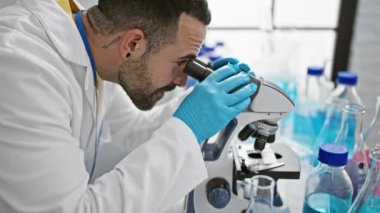 Genç İspanyol bilim adamı laboratuvar ortamında mikroskop kullanarak örnekleri inceliyor.