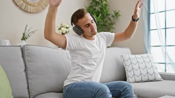 Молодий Чоловік Насолоджується Музикою Навушниками Затишній Вітальні Демонструє Релаксацію Сучасний — стокове відео
