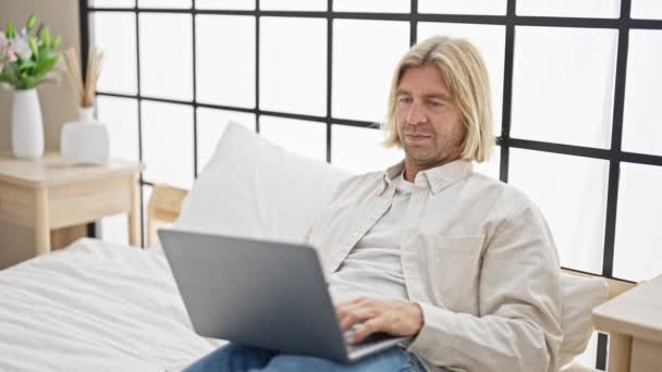 Homem Adulto Relaxado Com Longos Cabelos Loiros Usando Laptop Quarto — Vídeo de Stock