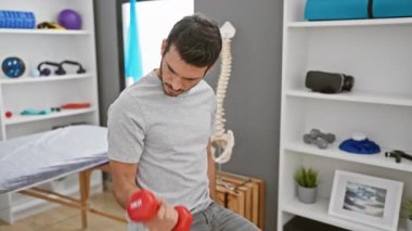 İspanyol adam modern bir rehabilitasyon kliniğinde dambıllarla egzersiz yapıyor, sağlık ve terapi örneğini veriyor..