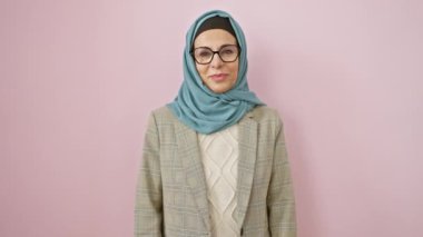 Keyifli orta yaşlı İspanyol kadın tesettüre baş parmak atıp başarısını işaret ediyor. İşaret işareti, izole edilmiş pembe arka planda mutlu..